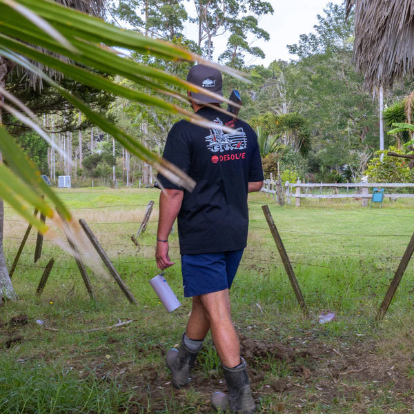 Person walking outdoors in a natural setting with trees and grass.