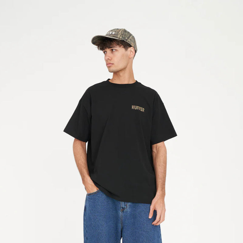 Man wearing a black t-shirt, blue shorts, and a cap on a white background