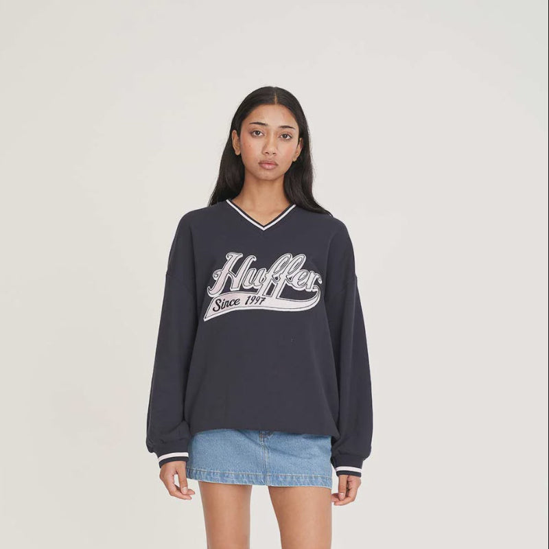 Person wearing a navy Huffer sweatshirt with a white logo on a plain background