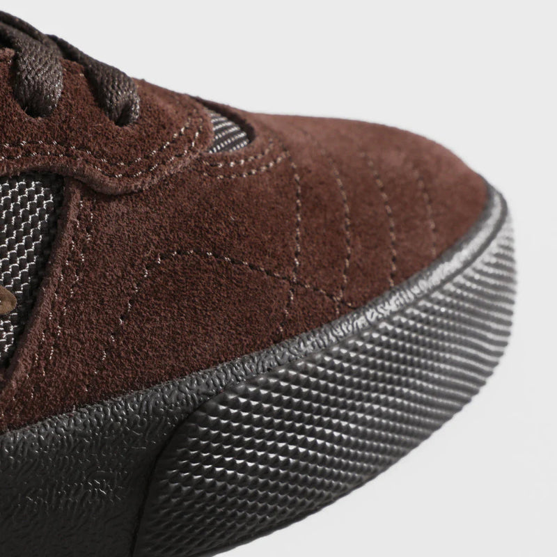 Close-up of a brown sneaker with a textured sole on a white background