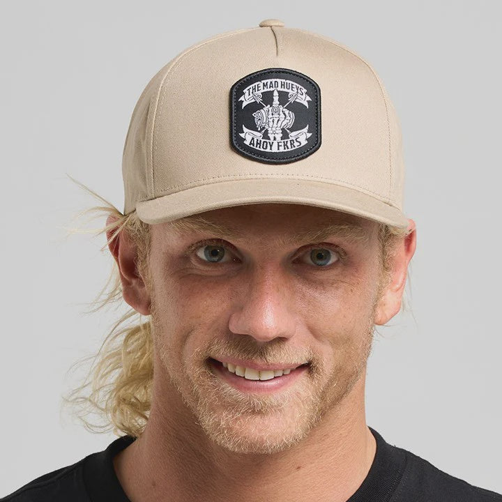 Man wearing a beige cap with a logo on a gray background