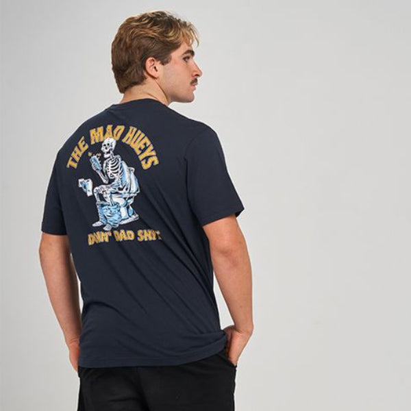 A man wearing a navy blue t-shirt with a large back graphic, black shorts, and black sneakers, photographed from behind against a light gray studio background.