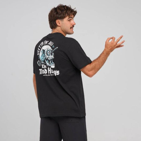 A man wearing a black t-shirt and shorts from behind, showing a large graphic print on the back with the text 'Hittin FK All' and 'The Mad Hueys'.