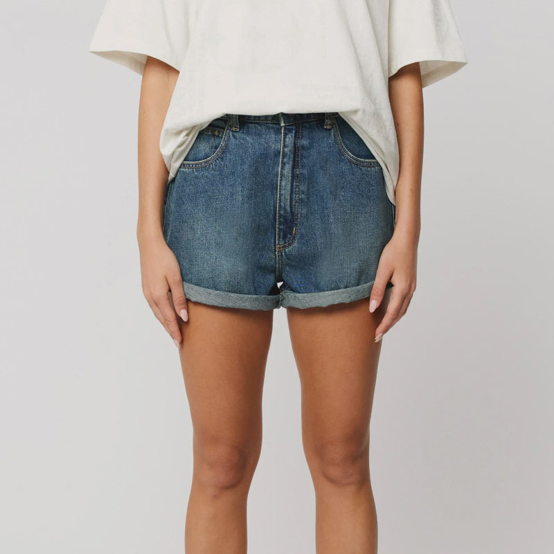Person wearing blue denim shorts on a plain background