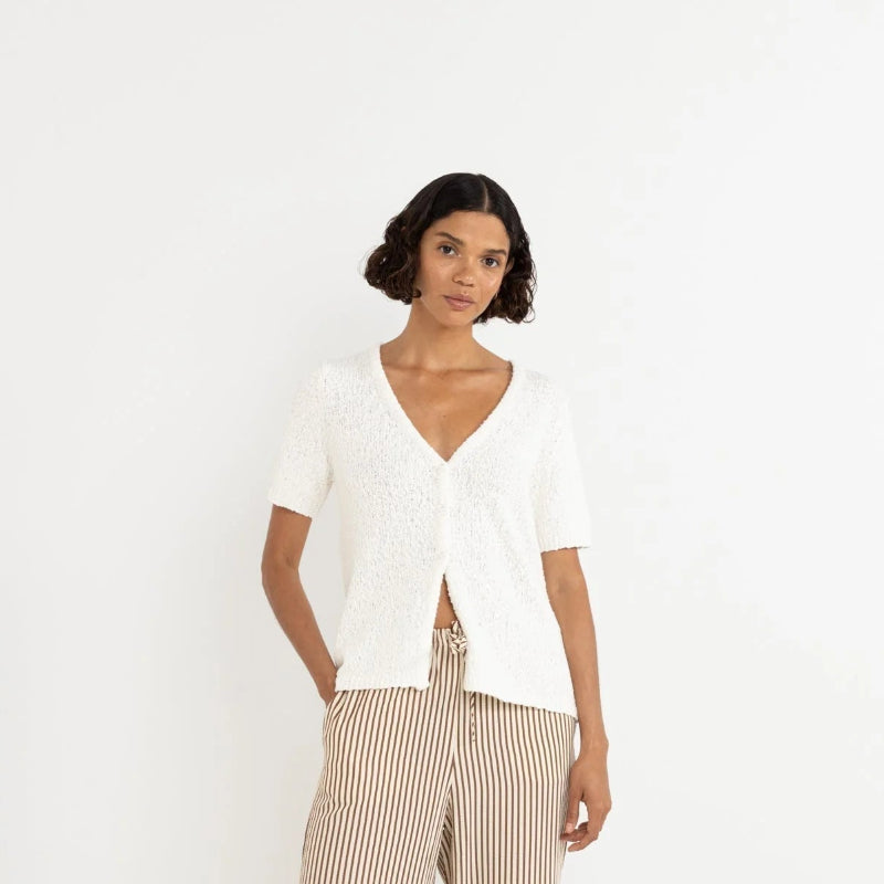 Woman wearing a white top and beige striped pants on a white background