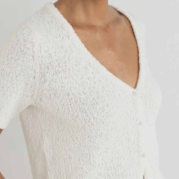 White textured sleeveless top worn by a person on a plain background