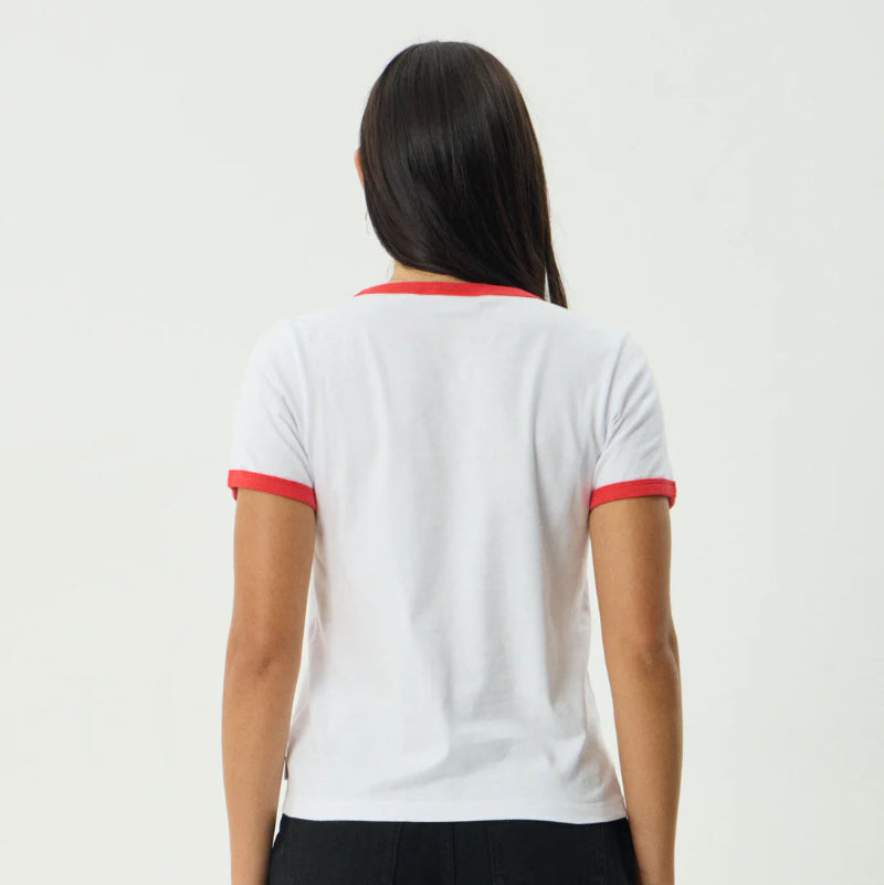 Person wearing a white t-shirt with red trim and black shorts on a plain background