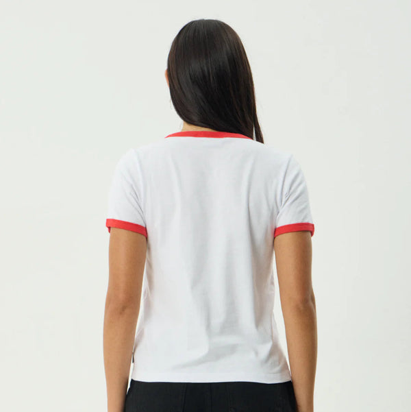 Person wearing a white t-shirt with red trim and black shorts on a plain background