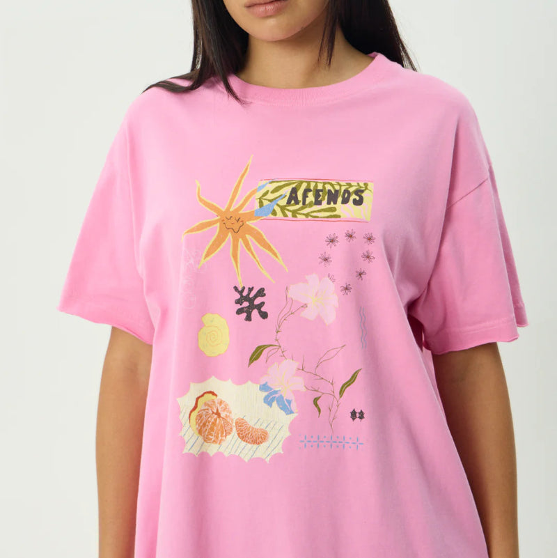 Person wearing a pink t-shirt with colorful graphics on a plain background