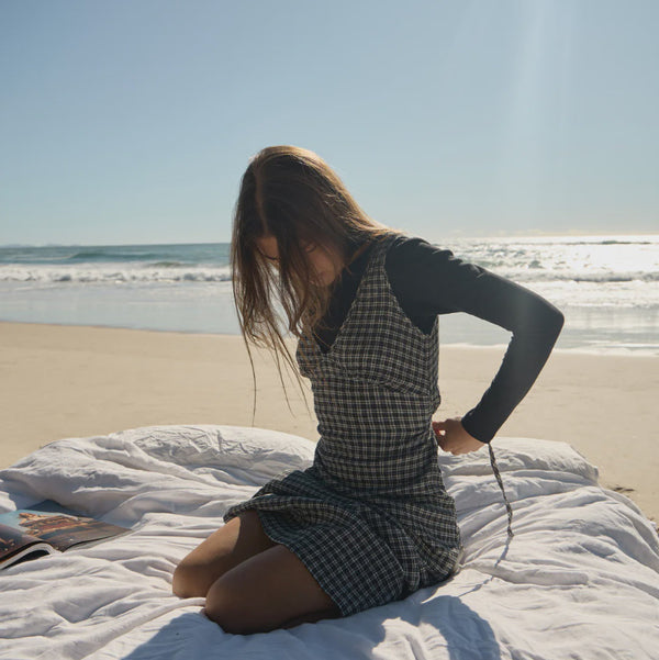 Woman sitting on a blanket at the beach with ocean view
