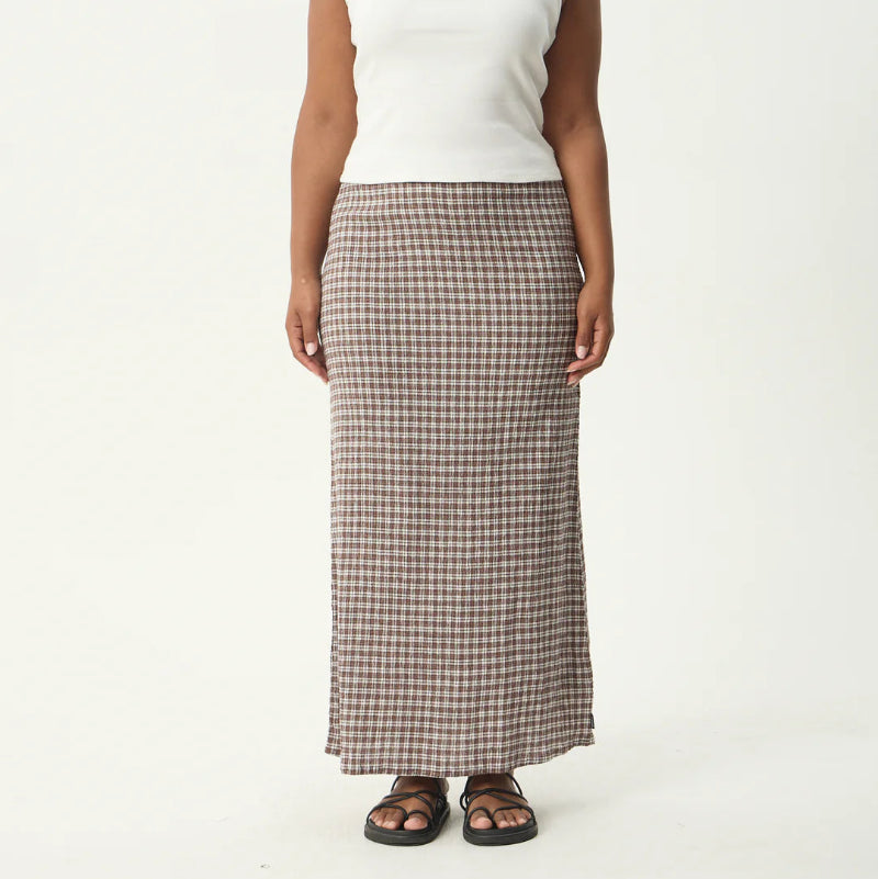 Woman wearing a white tank top and plaid skirt on a white background