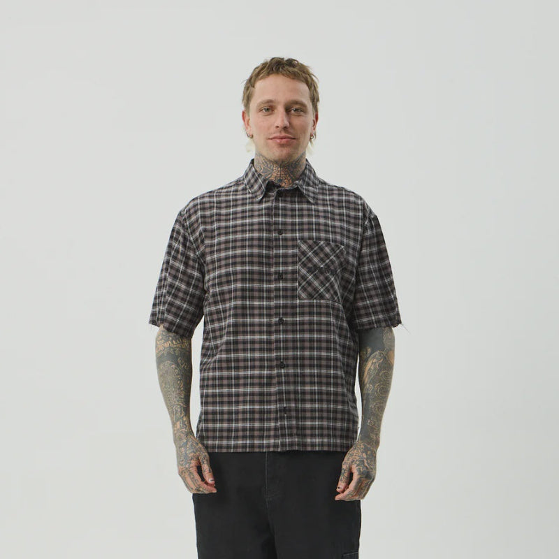Person wearing a plaid shirt and black pants on a white background