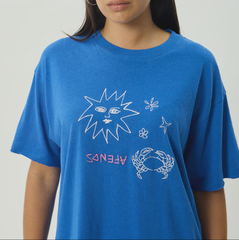 Person wearing a blue t-shirt with star and crab designs on a plain background