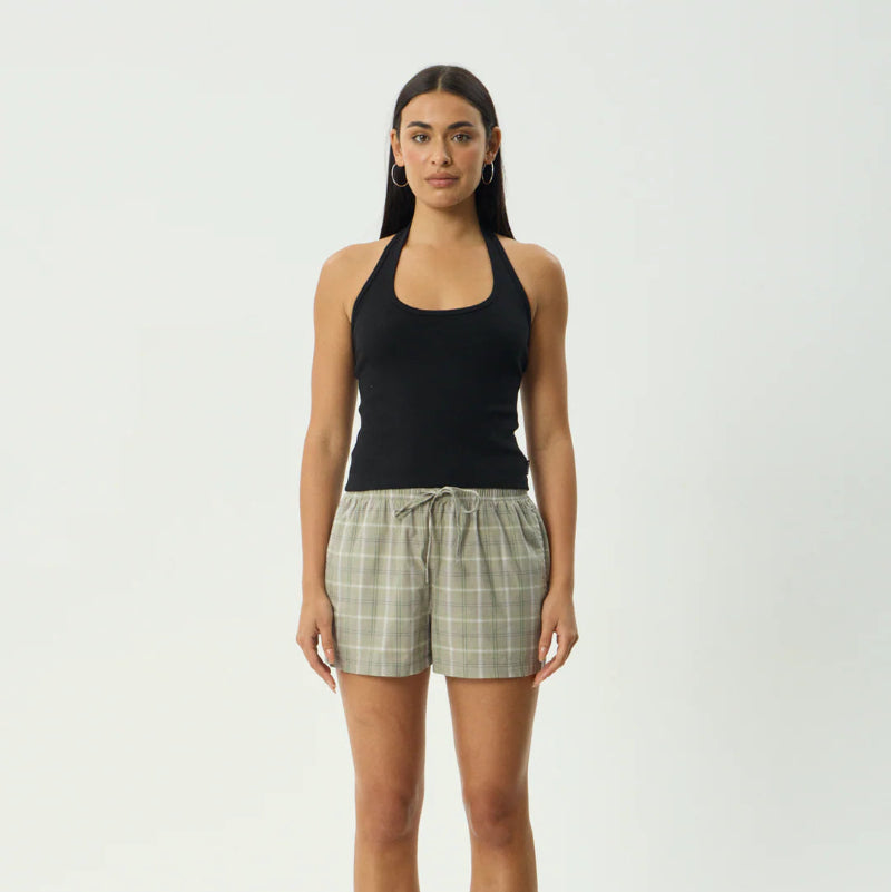 Woman wearing a black tank top and plaid shorts on a white background