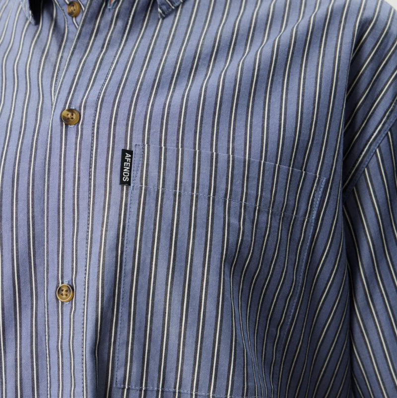 Close-up of a blue striped shirt with a brand label on a neutral background
