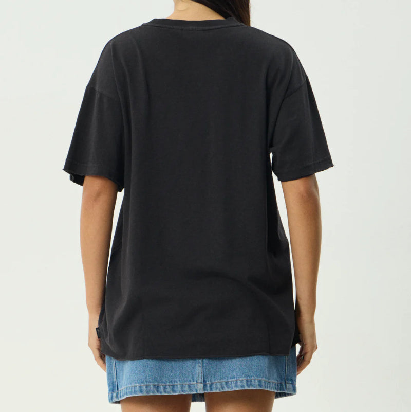 Person wearing a black oversized t-shirt and denim shorts on a plain background