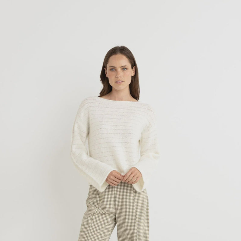 Woman wearing a white sweater and checkered pants on a white background