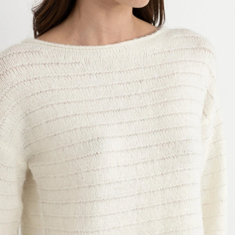 Close-up of a person wearing a textured white sweater against a plain background