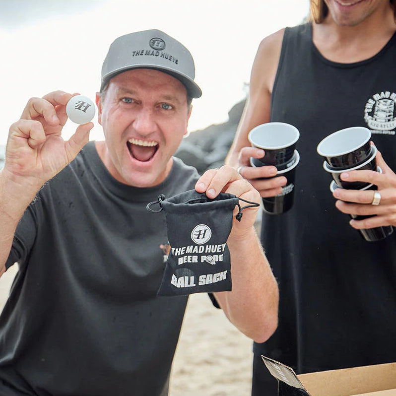 Two people holding branded cups and a bag on a beach