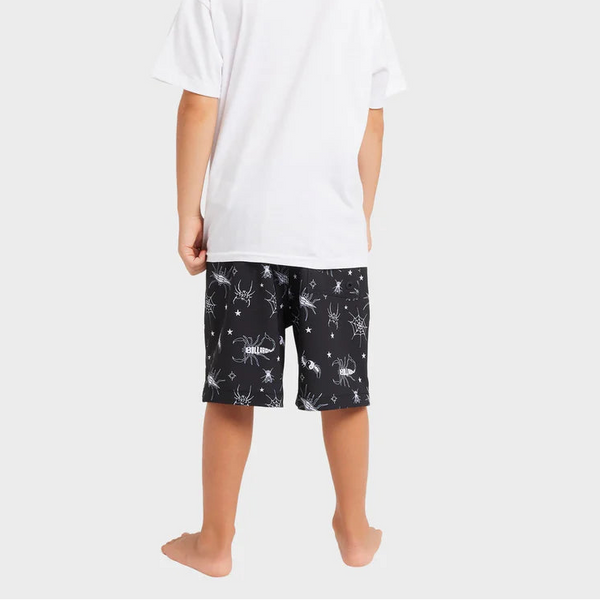 Child wearing a white t-shirt and black shorts with star pattern on a white background
