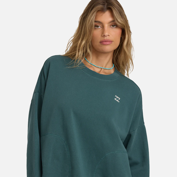 Woman wearing a teal sweatshirt with a small logo on a white background