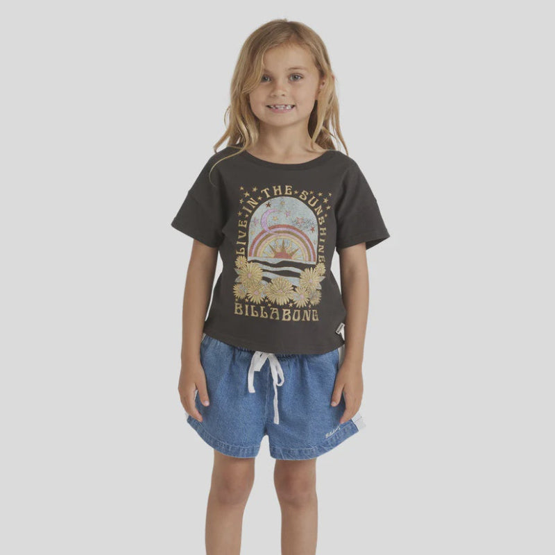 Child wearing a dark gray t-shirt with a graphic design and denim shorts on a light gray background