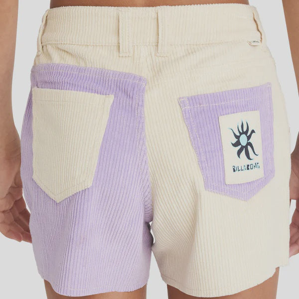 Beige shorts with purple patch featuring a logo on a plain background