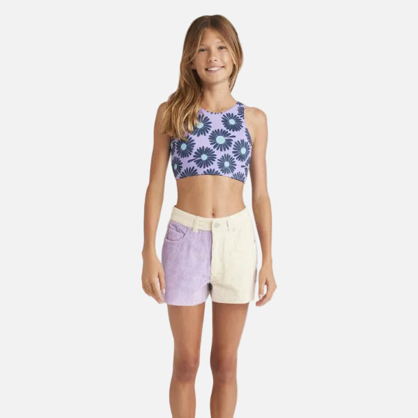 Young girl wearing a floral crop top and color-blocked shorts on a white background