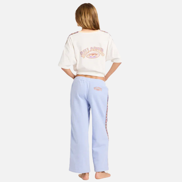 Person wearing a white crop top and light blue pants with branding on a white background