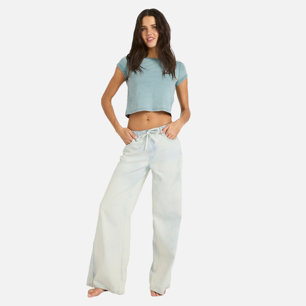 Woman wearing a light blue crop top and white wide-leg pants on a white background