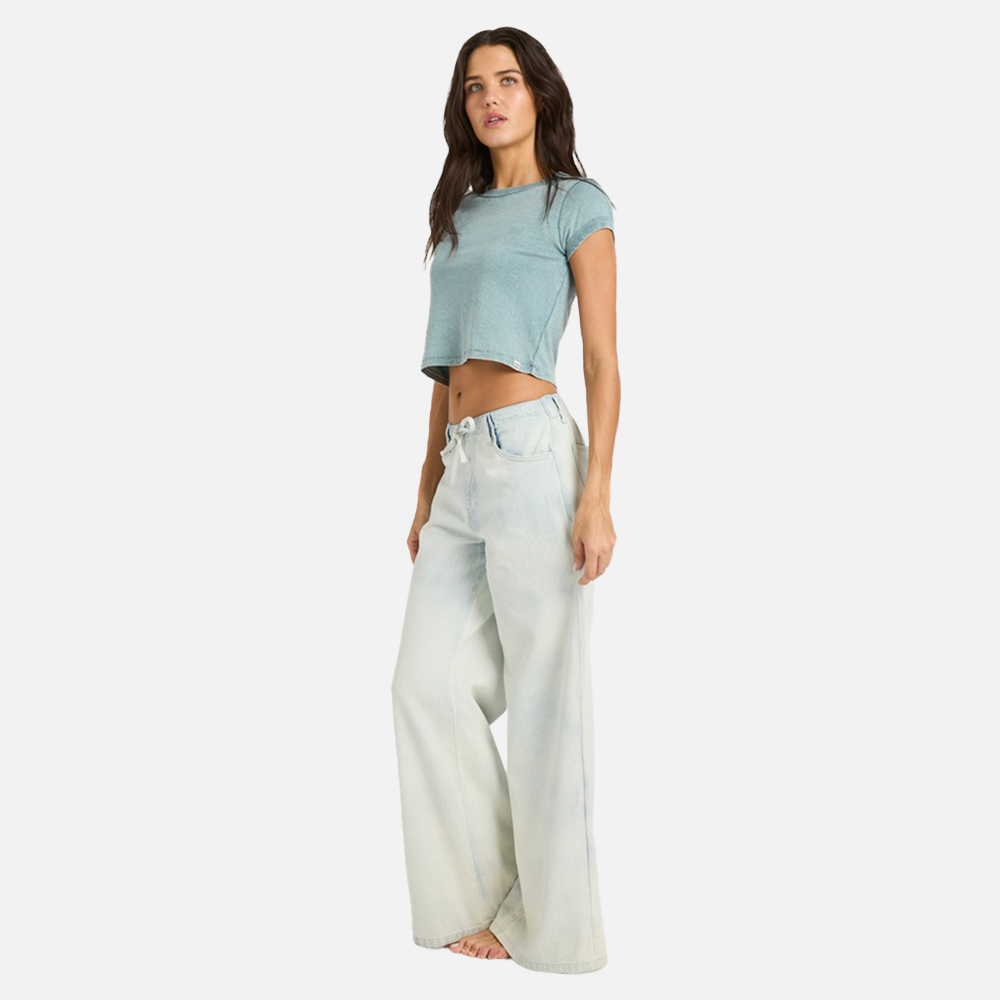 Woman wearing a light blue crop top and white wide-leg jeans on a white background