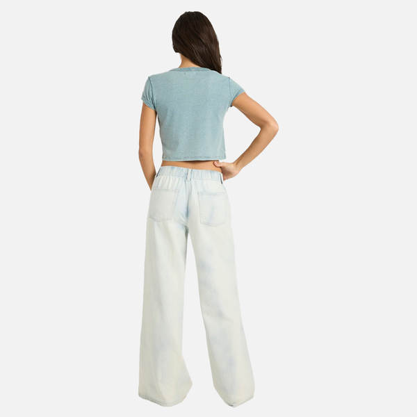 Woman wearing a light blue crop top and white wide-leg pants on a white background