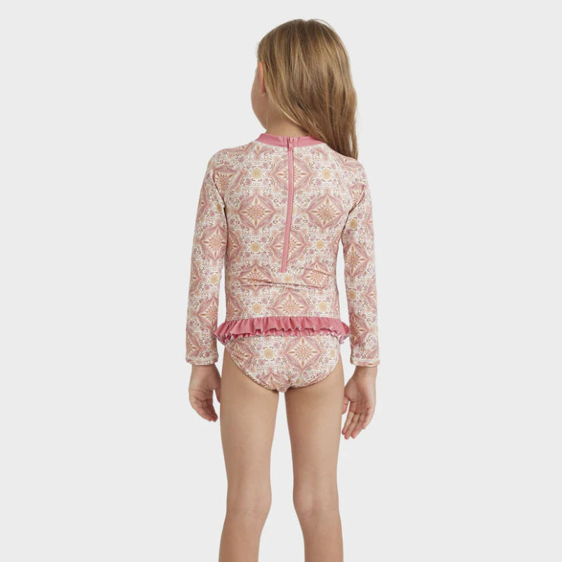 Child wearing a pink patterned swimsuit with long sleeves on a white background