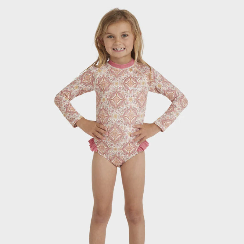 Young girl wearing a patterned long-sleeve swimsuit on a white background