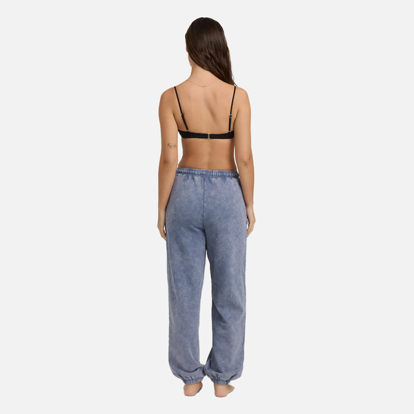 Woman wearing a black strappy top and blue denim pants on a white background