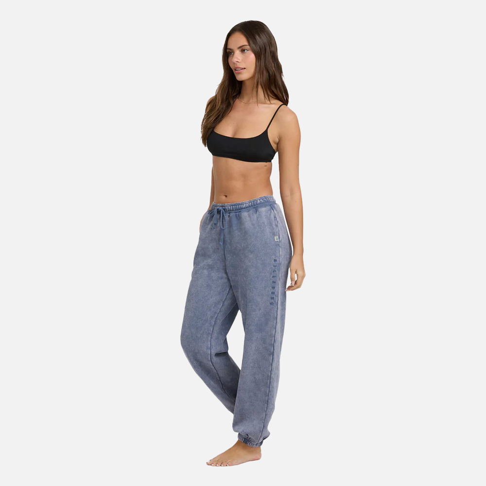 Woman wearing blue denim jogger pants and a black top on a white background