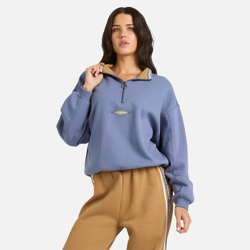 Woman wearing a blue pullover with a brand logo on a white background