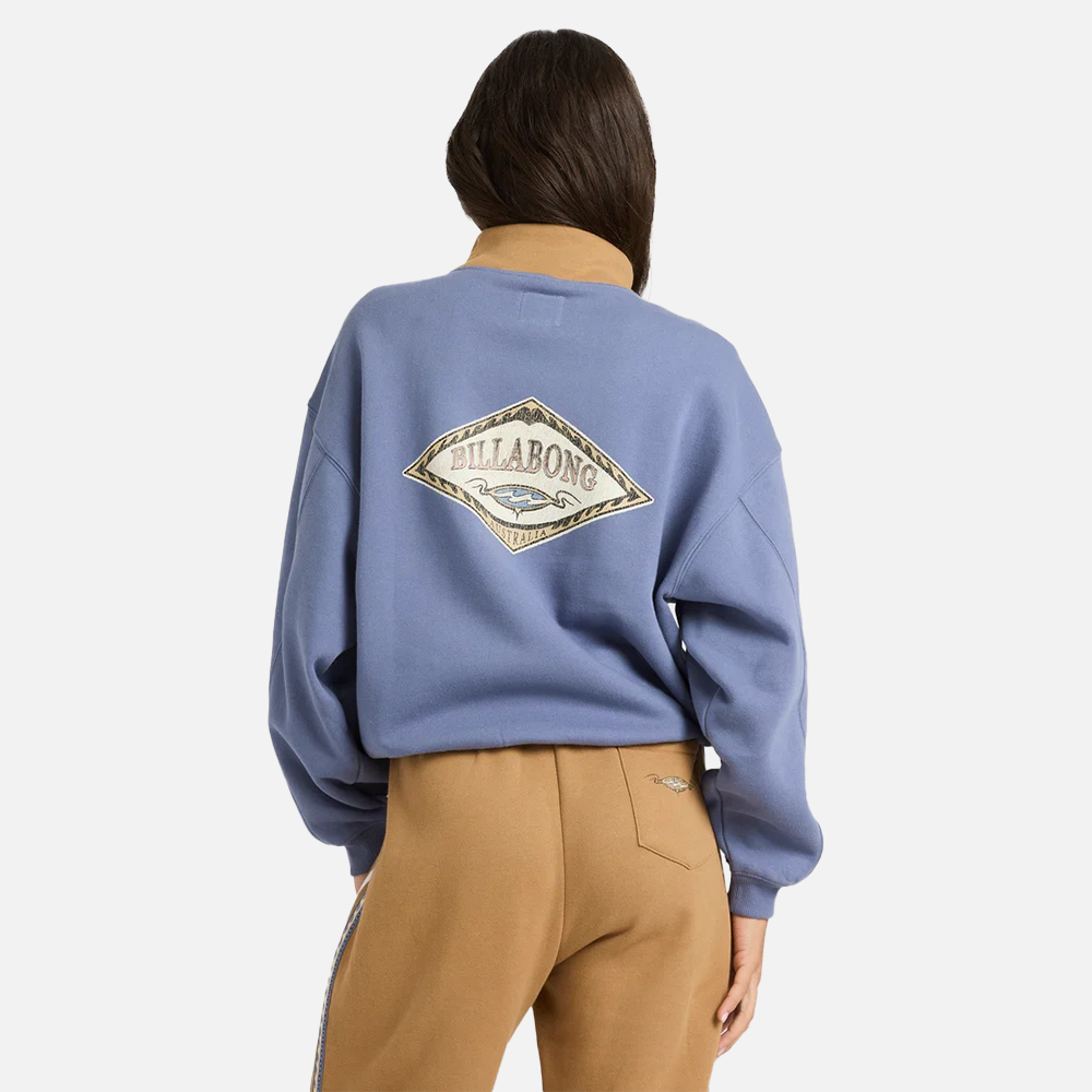 Person wearing a blue sweatshirt with a visible brand logo on the back, standing against a white background.