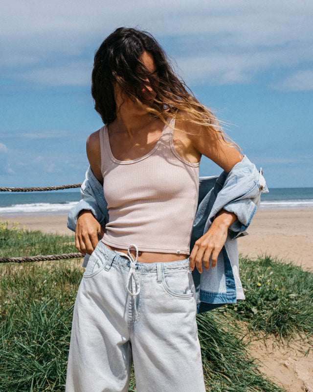 Woman standing on a beach with ocean and sky in the background