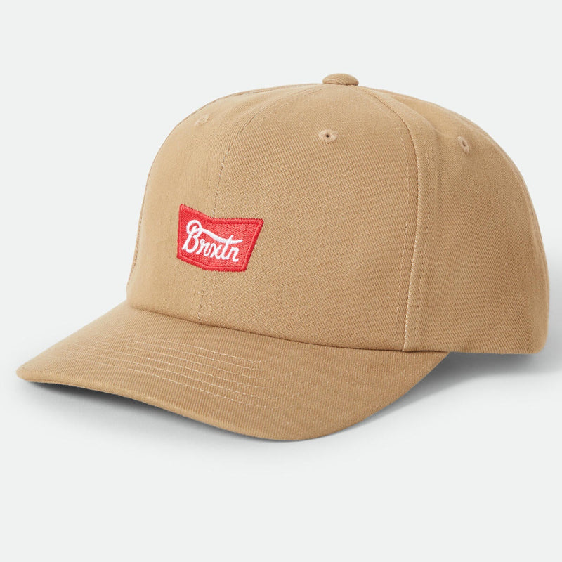 A tan cotton baseball cap with a red rectangular patch on the front featuring the white script logo 'Brodie'.