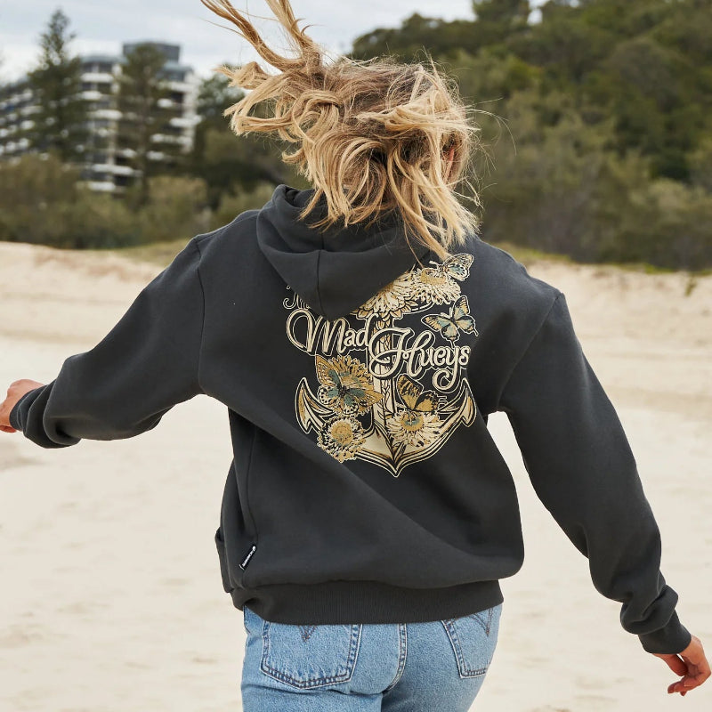 Person wearing a black hoodie with 'Mad Hueys' logo on a beach