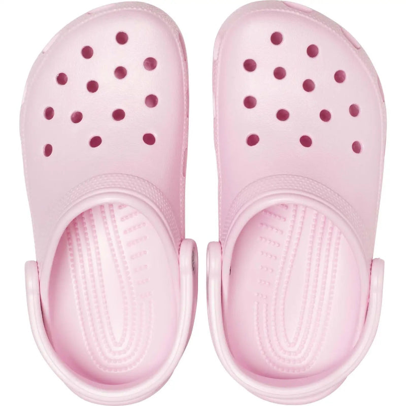 Pair of pink clogs with small holes on a white background
