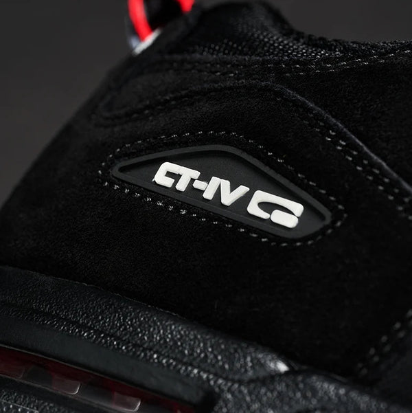 Close-up of a black suede and mesh sneaker showing the side logo patch with 'CT-IV G' in white, with a red pull tab visible at the top against a dark background.