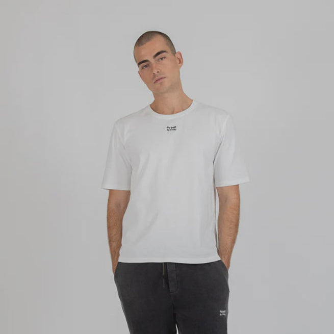 Man wearing a white t-shirt and black pants on a gray background