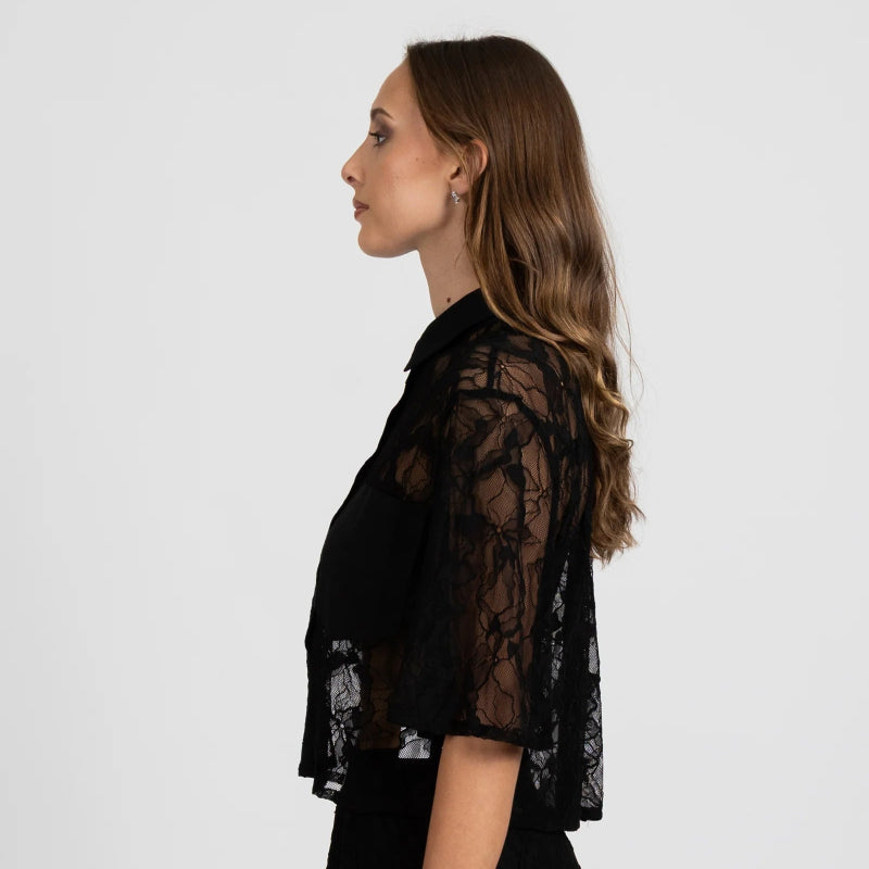 Woman wearing a black lace shirt against a white background