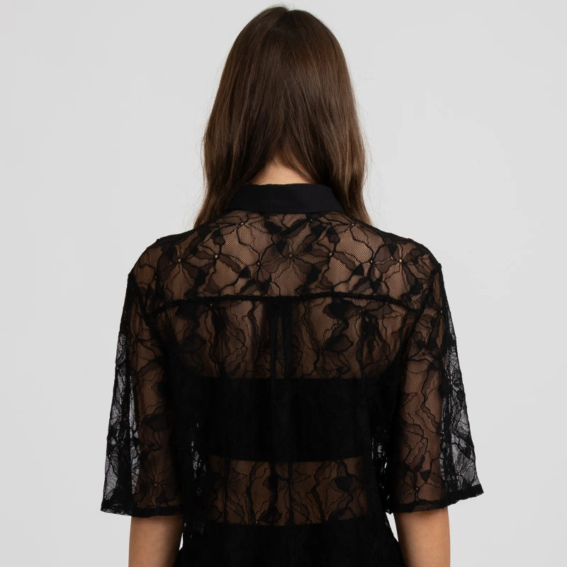 Black lace top worn by a person on a white background