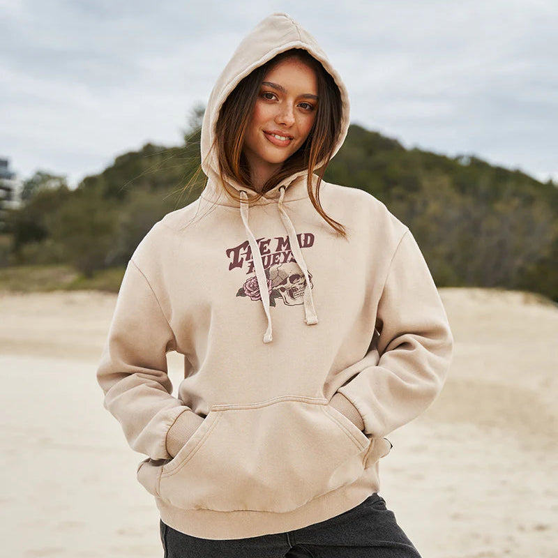 Person wearing a beige hoodie with a graphic design on a beach