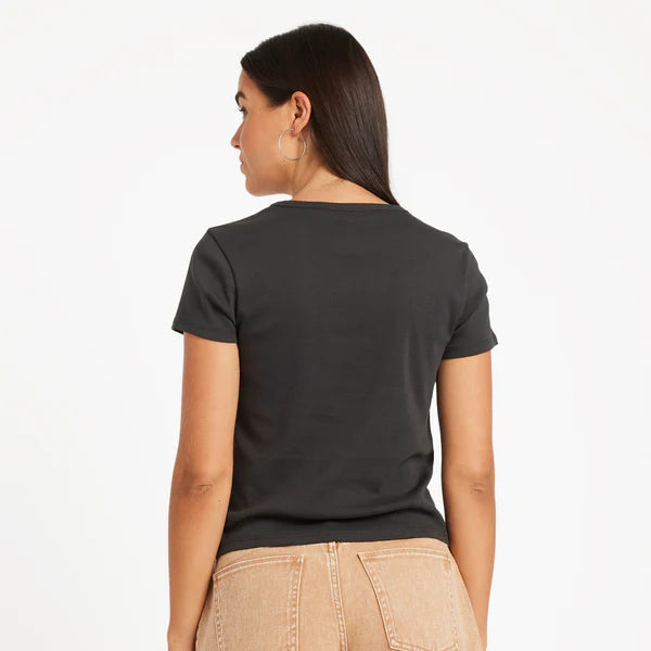 Person wearing a black t-shirt and beige shorts on a white background