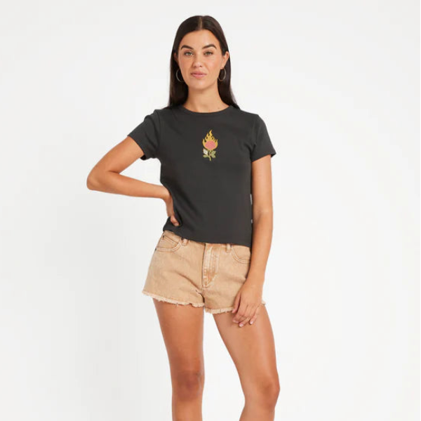 Woman wearing a black t-shirt with a graphic design and beige shorts on a white background