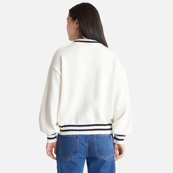 Person wearing a white sweater with black and white striped trim on a white background